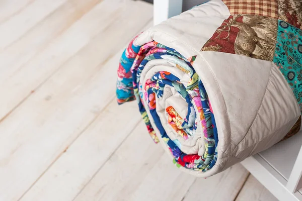 Lappendeken, naaien en mode concept - leuke kleurrijke doorgestikte deken op witte rekken met opbergvak in studio, witte vloer in een magazijn van afgewerkte producten, bovenaanzicht. — Stockfoto