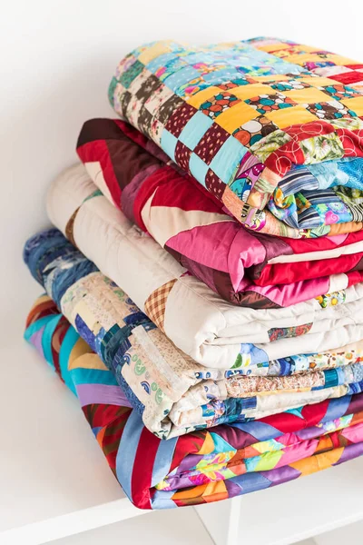 Patchwork, trapuntatura e concetto di moda primo piano su belle coperte colorate piegate e conservate in diverse file in altezza per lo stoccaggio, vendita di prodotti tessili cuciti su sfondo bianco . — Foto Stock