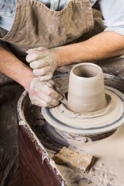 çanak çömlek, atölye, Seramik Sanat kavramı - ellerini bir adamın potters tekerlek ile inşaat, ham şamot, erkek usta parmakları form şeklinde bir kap bir sünger ve oyma aracı, üstten görünüm, dikey heykeltraşlık.