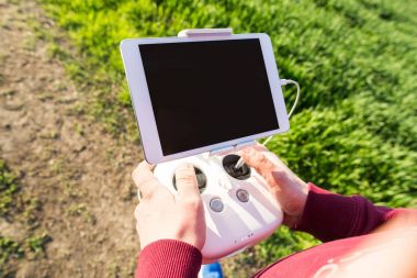 quadcopter uçuşları açık havada, havadan görüntü ve teknoloji hobi, eğlence kavramı - uçan dronun işlecinin arka plan yeşil çimen, seçici odak'elinde beyaz uzaktan kumanda.