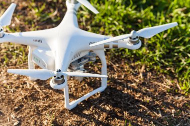 quadcopter yaz açık havada, havadan görüntüleri ve hobi, eğlence kavramı - quadrocopter indi çim toprakla, beyaz süper uçak gövde ile dört pervane ve yüksek kaliteli dijital fotoğraf makinesi.