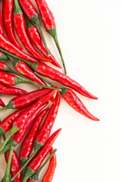 red hot chili peppers, popular spices concept - beautiful bunch of red chili hot pepper, fresh ripe pods with green peduncle on white background, flat lay, toop view, free space for text, vertical.