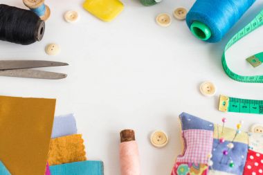Iğne işi, dikiş ve kavram - beyaz Resepsiyon, ölçme metre, pembe, mavi ve siyah iplik makaralar, araçları yakın çekim terzilik craft, renkli kumaş, iğne ve iğne yastığı, beyaz düğmeler, sabun artıkları.