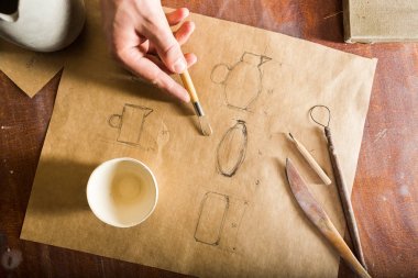 Seramik, heykel araçları, Seramik Sanat kavramı - kil testiler, tasarım ve mühendislik ürünleri, fincan ve ahşap masa üzerinde kalem çizim kalem üstten görünüm arka plan kahverengi.