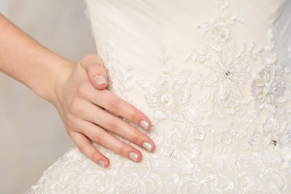 Fashionabla klänning, vacker modell, bruden och tillbehör koncept - vit brudklänning med broderi blommor, utsmyckad med strass och pärlor, hand slank kvinna på midjan. — Stockfoto