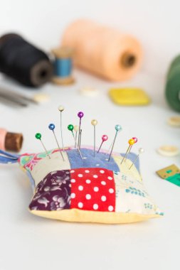 Iğne işi, dikiş ve kavram - yakın çekim ile delik deşik ve toplu iğneler, beyaz masa üzerinde dikiş el sanatları, ölçme metre, pembe, mavi ve siyah iplik makaralar, beyaz düğmeler, sabun, seçici odak, dikey.