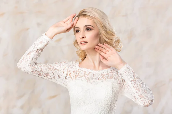 Vestido blanco de moda, hermosa modelo rubia, peinado de novia y el concepto de maquillaje - primer plano joven en vestido de fiesta de boda de pie en el interior sobre fondo claro, mujer bonita pose romántica . — Foto de Stock