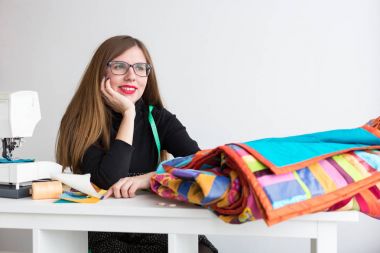 dikiş ve kapitone bir terzi - atölyesinde güzel genç bir dikiş makinesi, kumaş ve konu ile masada kollarını eğilerek kadın dinlenirken çalışma ve yan, seyir terzi