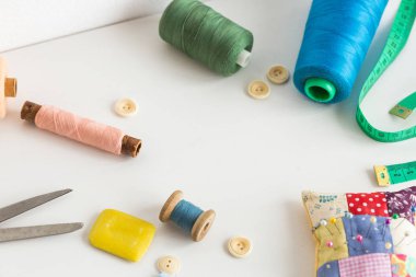 dikiş araçları, patchwork, terzilik ve moda kavramı - portre studio, renkli iplik makaralar, ölçme metre, düğmeler, beyaz masa üzerinde birçok çalıştı makas, iğne yastığı, iğne işi için donatım
