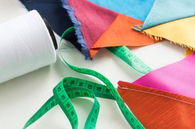 kapitone, dikiş ve moda kavramı - güzel patchwork üzerinde yakın çekim makro mavi, gri, sarı, mor ve turuncu dikişli kumaş artıkları, biriktirme beyaz iplik, metre, düz yatıyordu, en iyi görünümü.