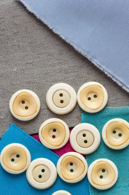 dikiş araçları, patchwork, terzilik ve moda kavramı - beyaz giyim düğmeleri kumaş, düz yatıyordu, en iyi görünüm, dikey mavi, gri yamalari parçaları üzerinde saçılma üzerinde yakın çekim.