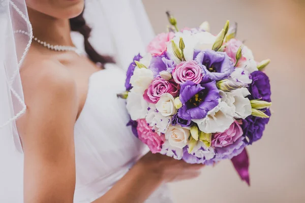 Elegante Braut in weißem Kleid und Schleier mit einem Brautstrauß aus violetten Rosen. Zärtlichkeit, Liebe, Hochzeitskonzept. — Stockfoto