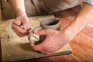 çanak çömlek, taş, Seramik Sanat kavramı - closeup usta ellerde kolu Kupası aracıyla, ana parmak inşaat parçaları şamot, masanın arkasında bir atölye genç erkek tezgahı ile bağlanma