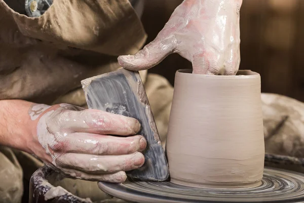 Tembikar, lokakarya, konsep seni keramik close-up pada tangan laki-laki memahat perkakas baru dengan alat dan air, mans jari-jari bekerja dengan roda tembikar dan petasan mentah, pandangan dekat depan . — Stok Foto