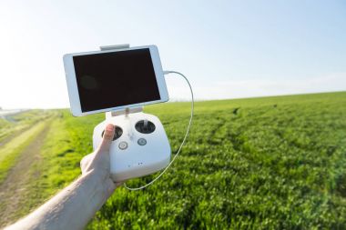 quadcopter uçuşları açık havada, havadan görüntü ve teknoloji hobi, eğlence kavramı - beyaz dron uzaktan kumanda el pilot yeşil çim alan ve mavi gökyüzü arka plan üzerinde mans.