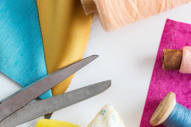 dikiş, dikiş, patchwork ve moda kavramı - closeup araçları beyaz çalışma masası stüdyo, makas, mavi ve pembe konu, metre, adet renkli patchwork kumaş, makaralar üzerinde düz lay.
