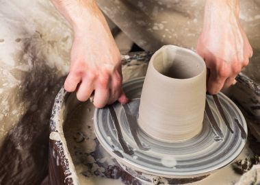 çanak çömlek, atölye, Seramik Sanat kavramı - yakın çekim altında ellerini yetişmek kapalı ile dize kesici yarı bitmiş mutfak eşyaları ürün Potters tekerlek, çiğ kil Kupası, önden görünüm üst yüzeyinden mans.