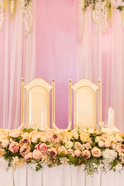 festive table for the bride and groom decorated with pink cloth and flowers.