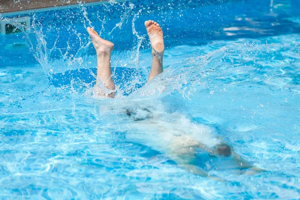 活動的な残り、ライフ スタイル、夏のスポーツ コンセプト - 青いプール水、ジャンプと表面、ホテルでのエンターテイメントの水泳選手のフィートまたは世帯のリアヤード後滴を水しぶきに男男ダイブ. — ストック写真