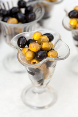 , hizmet, yiyecek ve içecek konsepti - catering closeup lezzetli yeşil ve siyah çekirdeksiz zeytin ile beyaz masa örtüsü, Festival dekorasyon hizmet, seçici odak, dikey tabloda birkaç vazo içinde.