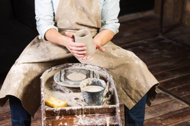 çanak çömlek, atölye, Seramik Sanat kavramı - ana oturur Potters direksiyonda unfired kil Kupası, bir adam bir taze ürün önce inceliyor erkek eller işleme, ön görünümü daha da.