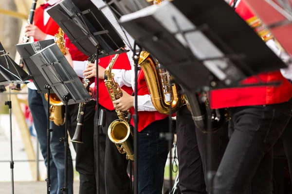 Brass band, müzik aleti, Orkestrası kavramı - saksafon ve klarnet, closeup levha müzik standları ve sax, müzisyenler kırmızı konser ceketler, seçici odak içinde Festival performansını.