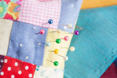 dikiş, patchwork, terzilik ve moda kavramı - renkli iğne, renkli patchwork kumaş parçaları, makro bir terzi Atölyesi'nde araçlar ile güzel dikişli iğnelik yatıyordu, en iyi görünüm düz.