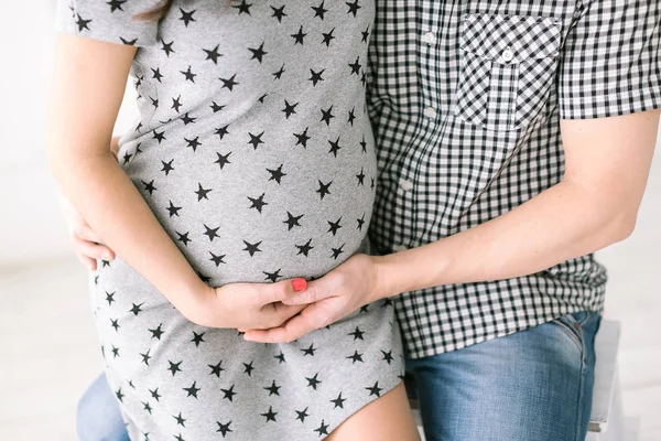 pregnancy, motherhood, birth of children concept - closeup on round belly of young future mother, embracing hands of expectant mother and men the future father support abdomen, expecting happiness.