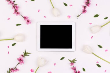 hassasiyet, iş, teknoloji kavramı. Lale ihale çiçekleri, brançlardan şeftali ağacı ve yeşil yaprakları gibi izole çiçek öğeleri çevrili dark ekran ile beyaz tablet Üstten Görünüm