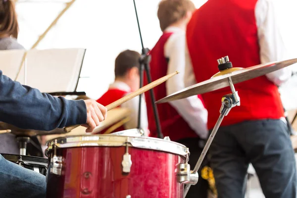 drum kit, jazz band music concept - closeup on hand of musician playing with stick on percussion instrument and ride cymbal, orchestra rehearsal before concert performance, selective focus.