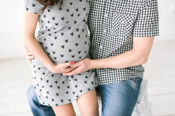 Pregnancy, maternity, love and care concept - closeup on round belly of young future mother, hands of expectant mother and men the future father gently support the abdomen, expecting happiness. — Stock Photo, Image