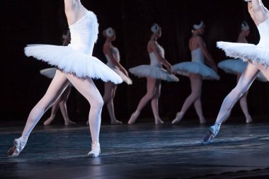 Bale, eğlence, sanat kavramı. ışık ve ağırlıksız beyaz balerinler saçlarını tutu ve tüyleri parlak elbiseler giyen dansing tiyatro karanlık sahne vardır.