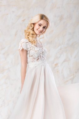 moda gelinlik, güzel sarışın model, açık renkli, bir gülümseme ile poz çok kadın kapalı lüks beyaz elbise genç kadında çarpıcı gelin saç ve makyaj kavram-.