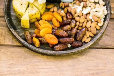 Yemek, ayarlama, ülke hayat kavramı. koyu renkli geniş düz ahşap plaka üzerinde tarihleri, Kuru Kayısı, badem, kaju ve baharatlar ile peynir vardır