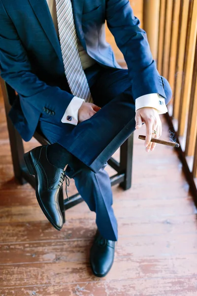 Belleza, estilo de oficina, concepto de masculinidad. guapo hombre de negocios con su encantador traje a cuadros azul, corbata a rayas y magnífico calzado de cuero negro fumar gran querubín — Foto de Stock