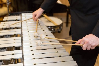 ksilofon Orkestrası, vurmalı çalgılar kavramı - closeup insan elinde dört Tokmaklar, siyah elbise, glockenspiel, sanat müzik, seçici odak sanatçı ile ahşap çubukları üzerinde oynama.