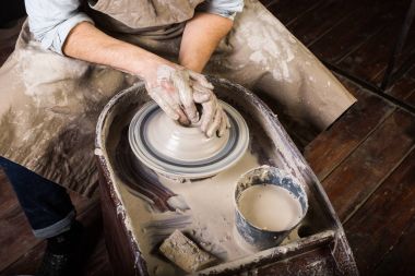 çanak çömlek, atölye, Seramik Sanat kavramı - yakın kadar potters çalışmaya tekerlek ile ham kil ve eller adamın, bir erkek bir kap ile parmak, önlük, üstten görünüm ana heykeltraşlık.