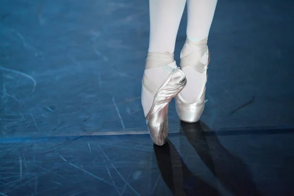 spectacle, dancing, equipment concept. two small aesthetic feet in beautiful pink pointe shoes of ballerina, dancing on the scratched floor of the theater stage