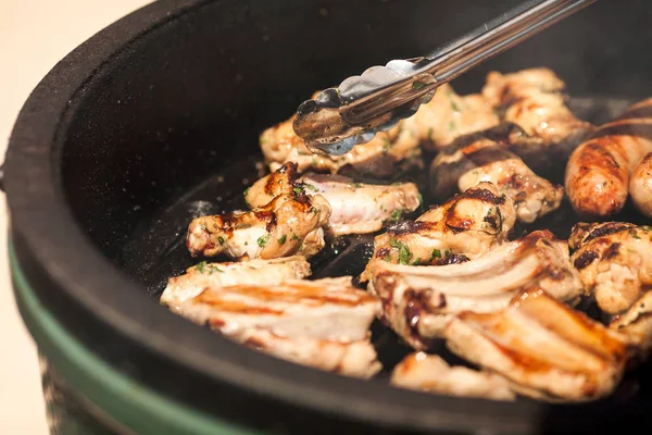 et yemek tarifleri, gıda ve piknik kavramı - Domuz kaburga üzerinde bir özel ızgara tava açık havada yemek bile metal mutfak maşa tarafından yemek pişirmek için dönüm güneşli gün, kavrulmuş sosis ile lezzetli sulu adet.