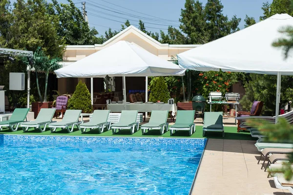 otel dinlenme, tatiller ve yaz yüzme kavramı - closeup güzel Havuzu Açık mavi su ve şezlong ile büyük beyaz çadır, güneşli resort eğlenceleri veya zengin villa arka altında dinlenmek için.