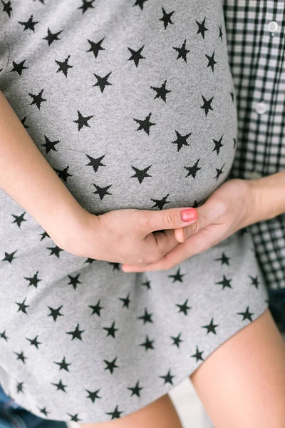 Terhesség, anyaság, születési gyermekek koncepció - Közelkép a kerek hasa fiatal jövő anya, a kezében a várandós anya és a férfiak a jövőben apja finoman támogatják a has, függőleges. — Stock Fotó