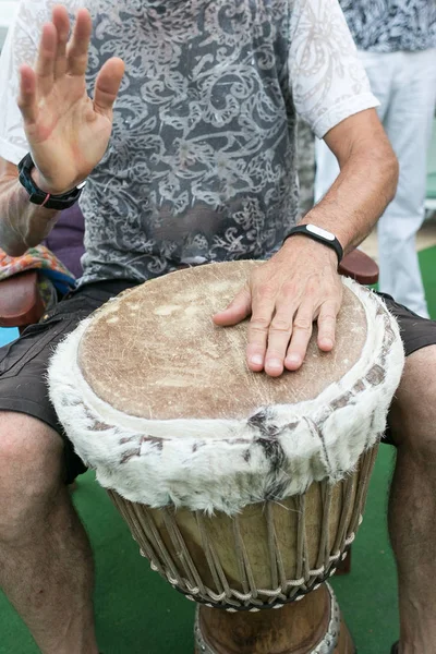 drum, percussion instruments and culture concept - closeup on hands of musician playing with traditional african djembe, summer outdoors concert performance, selective focus, vertical.