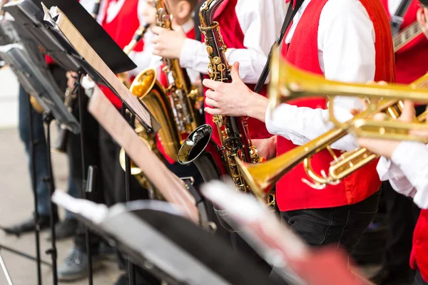 Instrumentos musicais de orquestra, conceito de banda de bronze - conjunto de músicos tocando trompete e saxofone em trajes de concerto, stands de música close-up e mãos masculinas com equipamentos, foco seletivo . — Fotografia de Stock