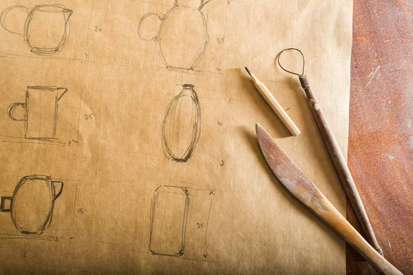 Fabricação de cerâmica, ferramentas artesanais, conceito de arte cerâmica - desenho de faiança, lápis e ferramentas na mesa de madeira, fundo marrom, vista superior . — Fotografia de Stock