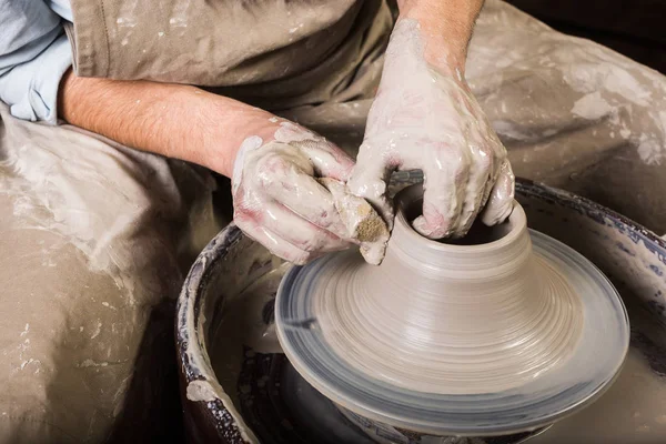 Keramik, verkstad, keramik konst koncept - närbild på arbetande keramiker hjul med rå eldfast lera och mans händer, manliga fingrar skulptera nya redskapen med en svamp och vatten, ovanifrån. — Stockfoto