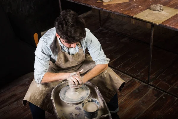 çanak çömlek, atölye, Seramik Sanat kavramı - ana formlar Potters kil tekerlek elle, dostum bükülmüş üzerinden iş, bir erkek bir kap ahşap masa, yakın dostum sculpts önlük ve gömlek, üstten görünüm.
