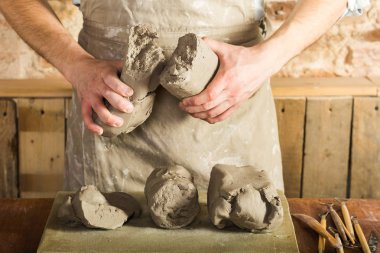 Potter, araçlar, Seramik Sanat kavramı - makro görünümü şamot, erkek bir önlük, bir Fransız masada hammadde ile giyinmiş büyük parçalarını tutan genç ustanın ellerinde.