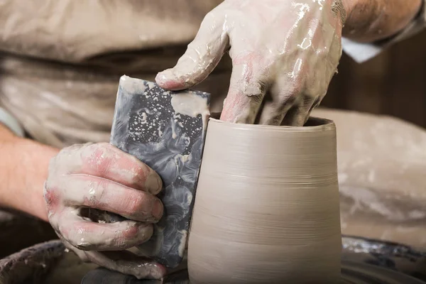 Workshop, aardewerk, keramiek kunst concept - close-up op mannelijke vingers beeldhouwen nieuwe gebruiksvoorwerp met een tools en water, mans handen werken met pottenbakkers wiel en ruwe brand clay, sluiten. — Stockfoto