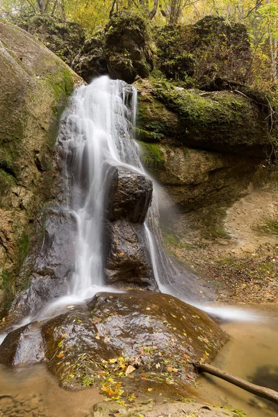 water resources, environment, landscape concept. little natural waterfall that placed between stones of the cliff, they are all covered by moss and some plants, bushes