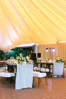 aydınlatma, kutlama, mutluluk kavramı. Ziyafet için hazırlanan günbatımı çadır gibi büyük sarı Restaurant, tüm tabloları yemekleri ve çiçekler ile servis edilir ve sahne ışıkları yanar